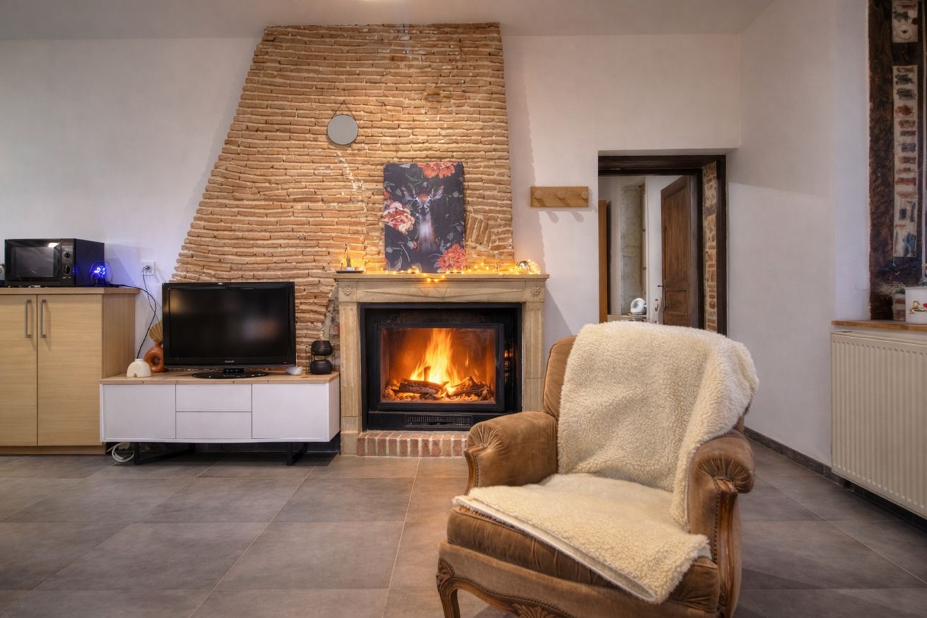 Salon avec cheminée et fauteuil – Gîte Les Pétillières